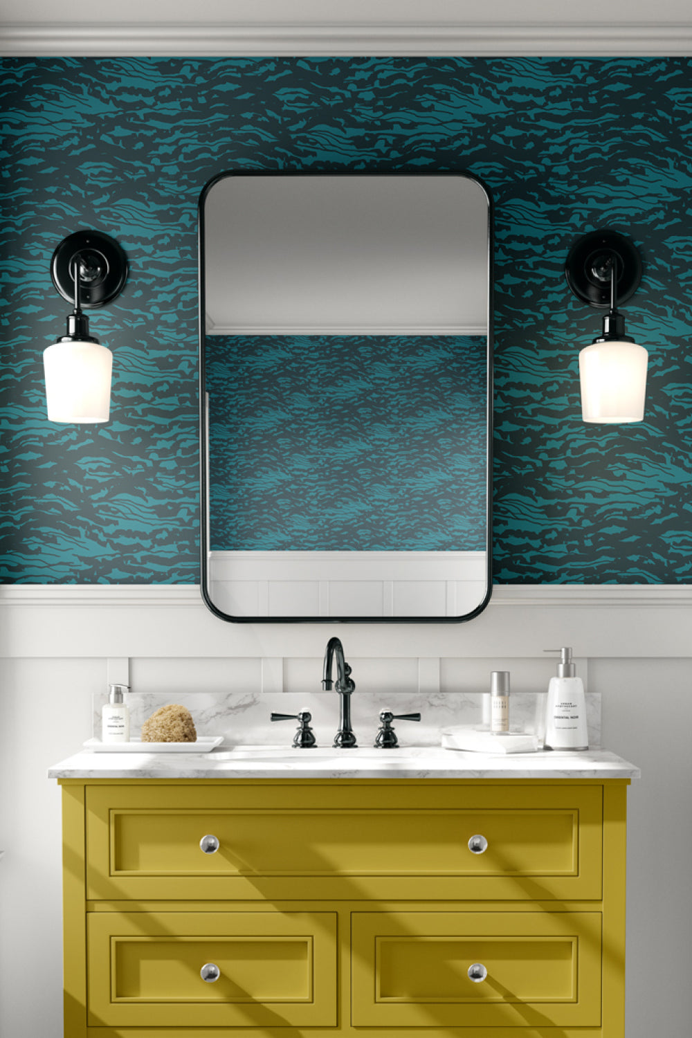 A styled bathroom vanity featuring a mustard yellow cabinet, white marble countertop, black faucet, a large black-framed mirror, and a bold teal and black patterned wallpaper on the wall. Designed by artist Leila Simon Hayes.