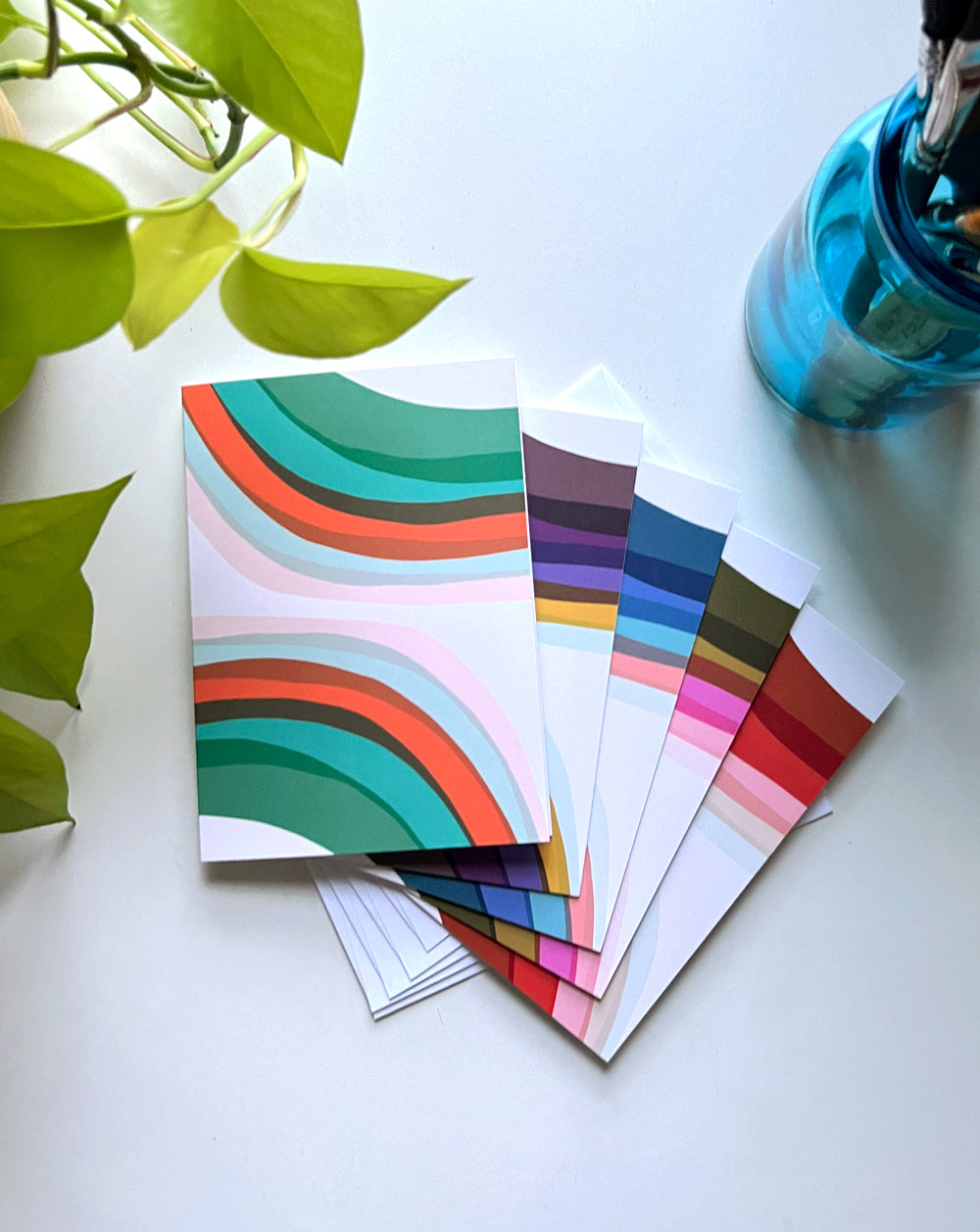 Rainbow painted designs on a pack of five folded card packs, designed by artist Leila Simon Hayes.
