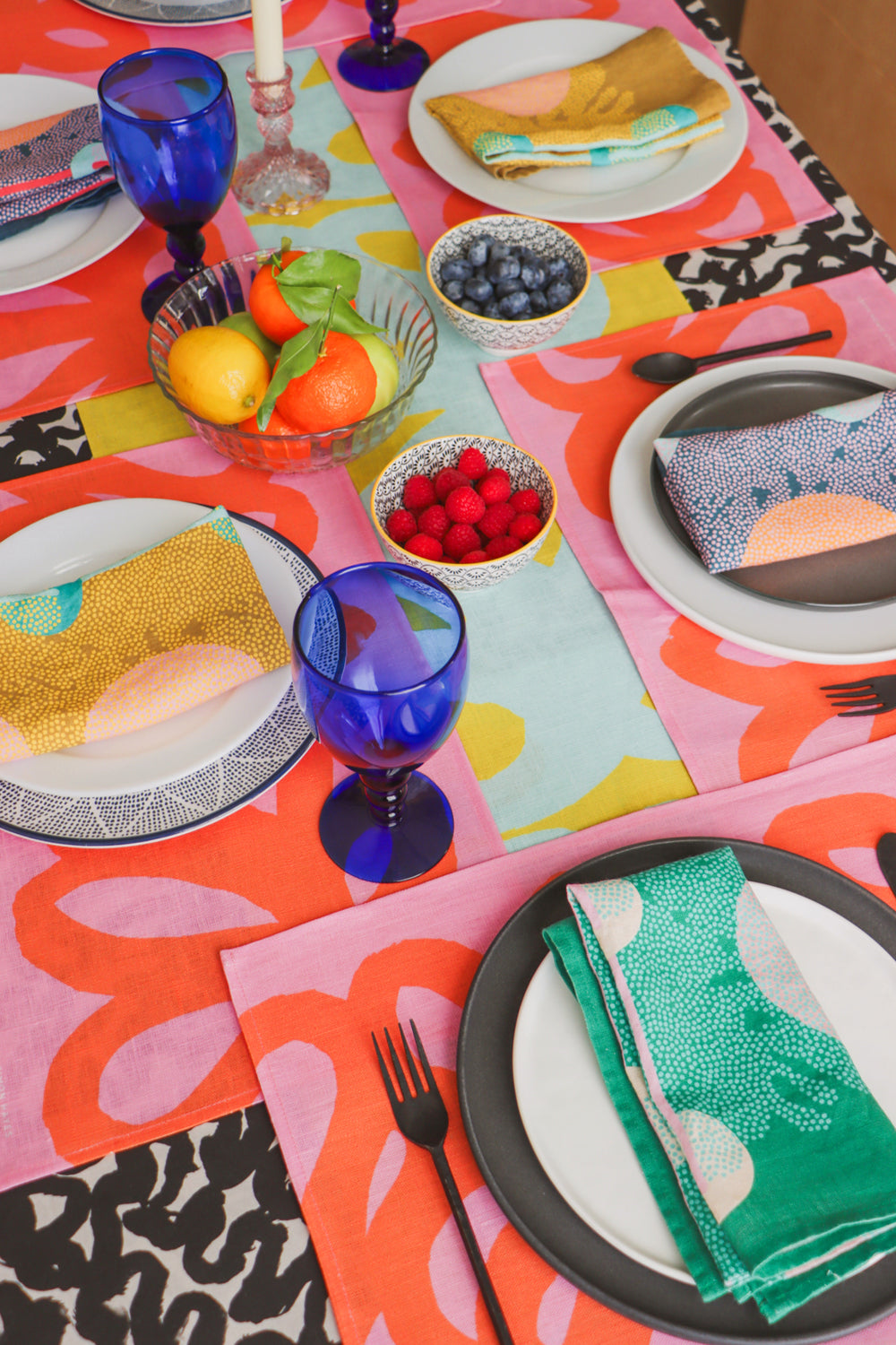 Colorful table setting ready for a brunch with colorful napkins, placemats, a table runner and a table cloth. Designed by artist Leila Simon Hayes.