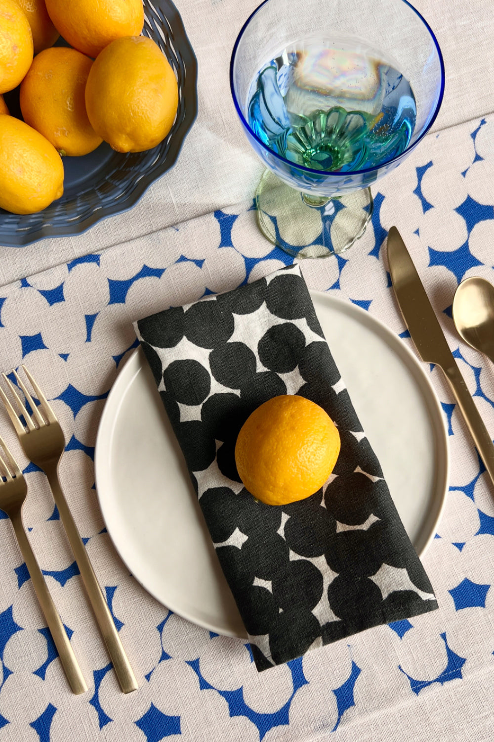 Table setting with a black and white polka dot patterned napkin and blue and white polka dot patterned placemat. Designed by artist Leila Simon Hayes.