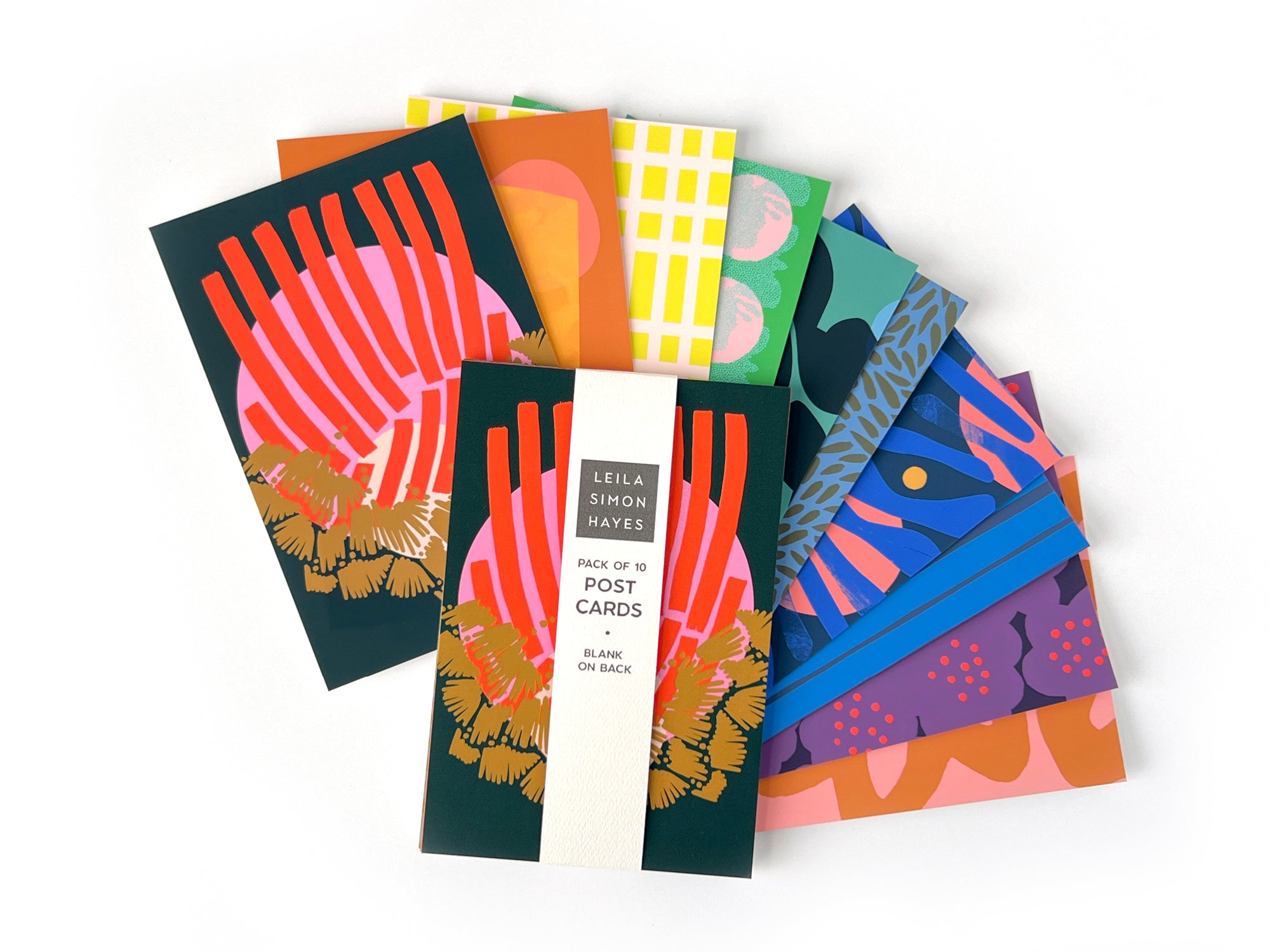 Pack of 10 colorful postcards with various hand-drawn designs, spread out on a white background. Designed by artist Leila Simon Hayes, postcards are blank on the back. 