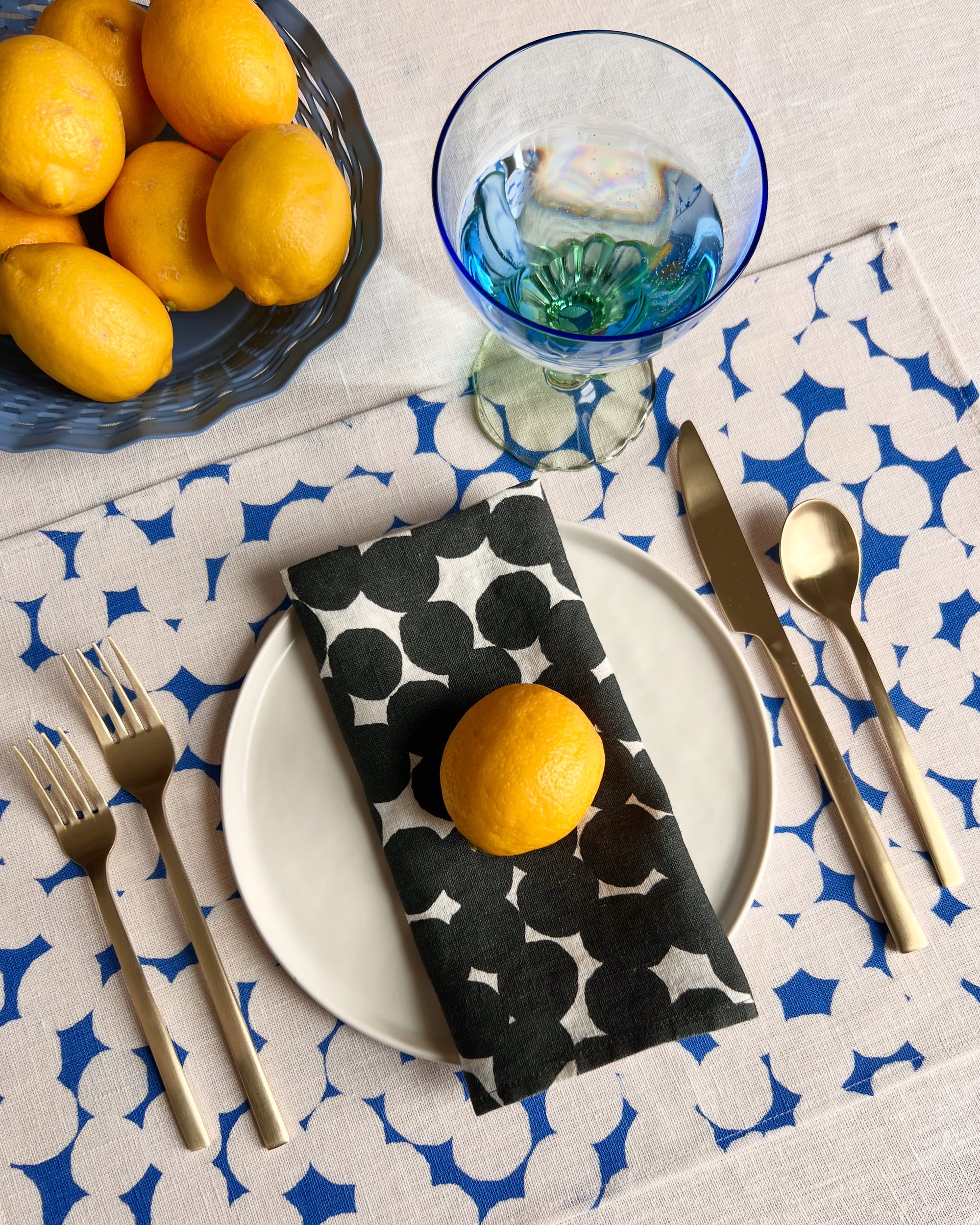 Decorative table setting, sky blue and white dot placemat, black and white dots linen napkin. Designed by artist Leila Simon Hayes