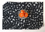 Set of black and white dot patterned placemats with a plate of oranges on a matching tablecloth.